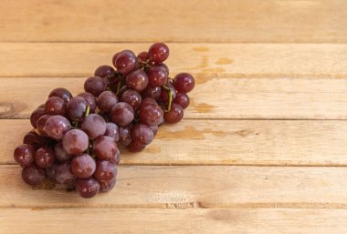 Bir demet pembe üzüm. Masa üzümleri tüketime hazır. Seçici odak noktasında ahşap arka plan. Meyve suyu ve reçel yapmak için meyve. Sarmaşık ürünü. Detoks meyveleri.