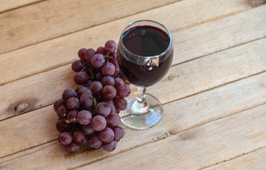 Bir demet pembe üzüm ve bir bardak doğal meyve suyu. Ahşap arka. Masa üzümleri tüketime hazır. Üzüm suyu ile kristal. Meyve suyu ve reçel yapmak için meyve. Sarmaşık ürünü. Detoks meyveleri.