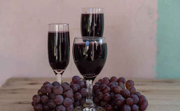 Bowl with grape juice and bunches of fresh grape on wooden surface. Grape juice is rich in several nutrients and can bring many health benefits. Detox drink.