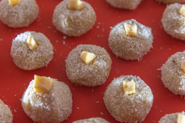 Homemade milk sweets called beijinho served on a red tray. Sweets for birthday party. Delicious desserts. Decorated kisses and served on a colorful plate.