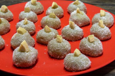 Homemade milk sweets called beijinho served on a red tray. Sweets for birthday party. Delicious desserts. Decorated kisses and served on a colorful plate.
