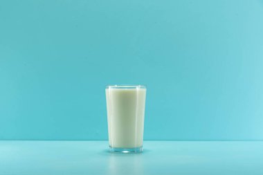 Glass cup with milk on the blue background. Calcium-rich food. Cow milk. Blue background.