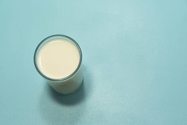 Glass cup with milk on the blue background. Calcium-rich food. Cow milk. Blue background.