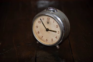 Ahşap yüzeyde eski ve eski bir çalar saat var. Klasik arka plan. Dekor objesi. Zaman çizelgesi. Analog saat. Koyu arkaplanda saat.