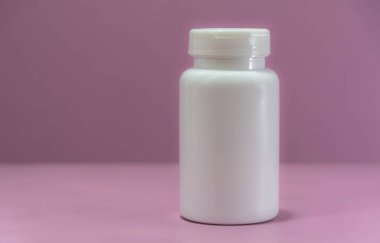 Pembe arka planda ilaç için beyaz plastik şişe. İlaç ambalajı. İlaç ve hap depolamak için bir şişe. Hastane malzemeleri..