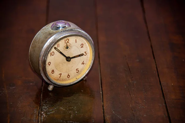 Old and retro alarm clock on wooden surface. Vintage background. Decor object. Time marker. Analog clock. Clock on dark background.