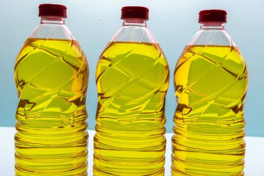 Mavi arka planda yenilebilir soya yağı olan plastik şişeler. Bitkisel yağ. Soya yağı, soya fasulyesinden elde edilen ve doymamış yağ, omega 3 ve 6 ve E vitamini bakımından zengin bir sebze yağı türüdür..