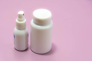 Tıbbi plastik sprey şişeleri ve pembe arka planda haplar. İlaç paketleri. Endüstriyel şişeler Genel ilaçlar.