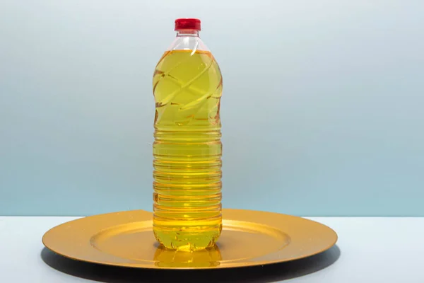 Plastic bottles with edible soy oil on yellow tray on blue background. Vegetable oil. Soy oil is a type of vegetable oil extracted from soy beans.