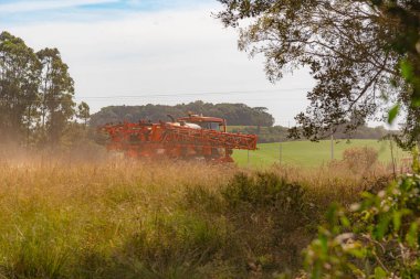 Toprak yolda ilerleyen tarımsal püskürtücü. Tarım makinesi. Güney Brezilya 'da tarım ve soya fasulyesi üretim bölgesi