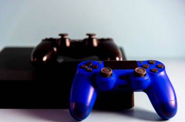 Işık arkaplanındaki kontroller ve oyun konsolu. Elektronik oyun aksesuarları. Video oyunu oyun platformu. Oyuncular için dilek öğesi. Modern, kablosuz oyun ve yön denetimi.