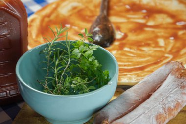 Ev yapımı pizza hazırlamak için mutfak malzemeleri. Maydanoz, biberiye, soğan, pepperoni ve domates sosu. Kırmızı soslu ve soslu pizza hamuru..