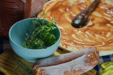 Ev yapımı pizza hazırlamak için mutfak malzemeleri. Maydanoz, biberiye, soğan, pepperoni ve domates sosu. Kırmızı soslu ve soslu pizza hamuru..