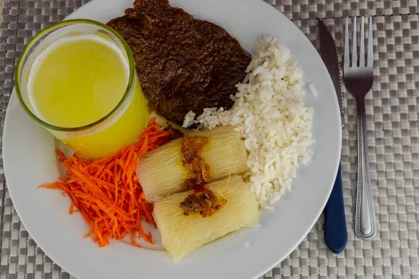 Brazilian food dish with steak and rice and carrots and cassava with an eye. Executive lunch. Homemade and seasoned food. Roast beef with sauce and salads. Homemade delights. Typical dish of Brazil.