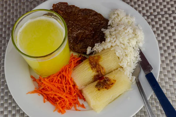 Brazilian food dish with steak and rice and carrots and cassava with an eye. Executive lunch. Homemade and seasoned food. Roast beef with sauce and salads. Homemade delights. Typical dish of Brazil.