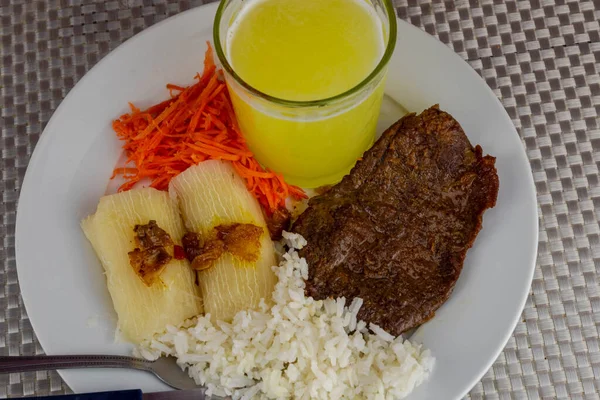 Brazilian food dish with steak and rice and carrots and cassava with an eye. Executive lunch. Homemade and seasoned food. Roast beef with sauce and salads. Homemade delights. Typical dish of Brazil.