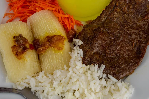 Brazilian food dish with steak and rice and carrots and cassava with an eye. Executive lunch. Homemade and seasoned food. Roast beef with sauce and salads. Homemade delights. Typical dish of Brazil.