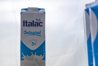 Beyaz arka planda bir kutu süt aydınlatıldı. Tam kremalı süt paketleme kutusu. Süt ürünlerinin ticari ambalajı. Reklamlar ve ürün tasarımı.