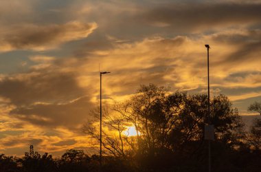 Braz 'da bir alışveriş merkezinin otoparkında dramatik bir gökyüzü ve gün batımı silueti.