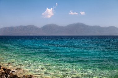 çakıl plajı ve sörf, arka planda dağlar. Yunanistan. Girit