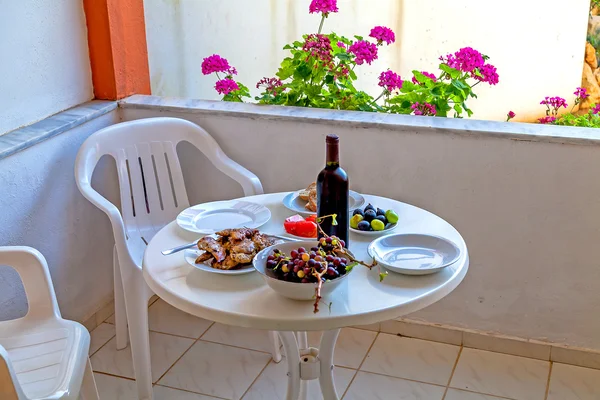 Lehký oběd na balkóně. Víno, grilovaná masa, fíky, hroznové a rajčaty. — Stock fotografie