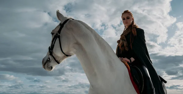 Mladá Vikingka s červenými vlasy jezdí na koni. Dramatické světlo. Hra na hraní rolí — Stock fotografie
