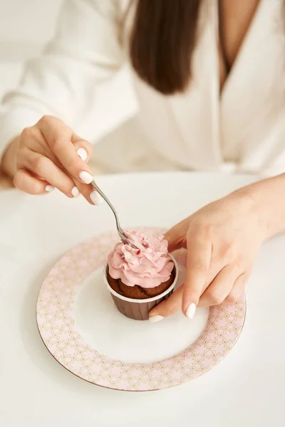 Mulher comendo cupcake rosa no prato, por colher pouco — Fotografia de Stock