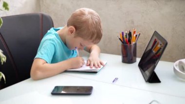 Genç çocuk evde tabletle öğreniyor. Karantinada uzaktan öğrenme. İzolasyon. Ev ödevi