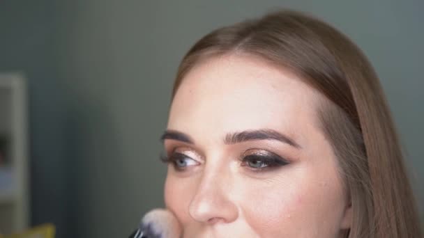 Maquillaje artista haciendo corrección facial por pincel. Ojos brillantes, purpurina — Vídeos de Stock