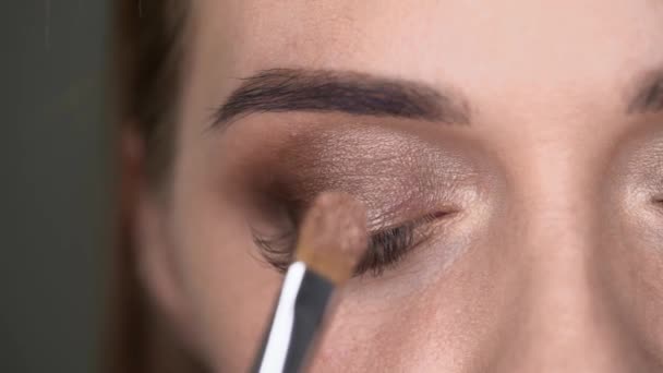 Make-up artist gör makeup till kvinnan med blå ögon med pensel och ögonskuggor — Stockvideo