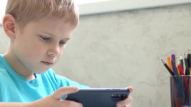 Genç çocuk evde akıllı telefonla oynuyor. Karantina