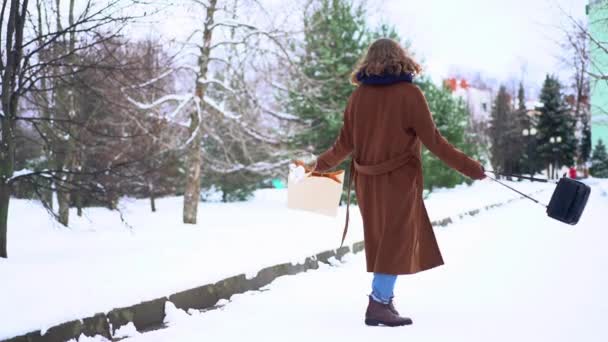 Ung vacker kvinna i stickad halsduk stående i parken med shoppingväska — Stockvideo