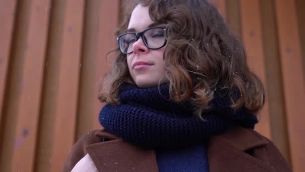 Young beautiful woman in knitted red hat and scarf enjoying and catching snow. Winter — Stock Video