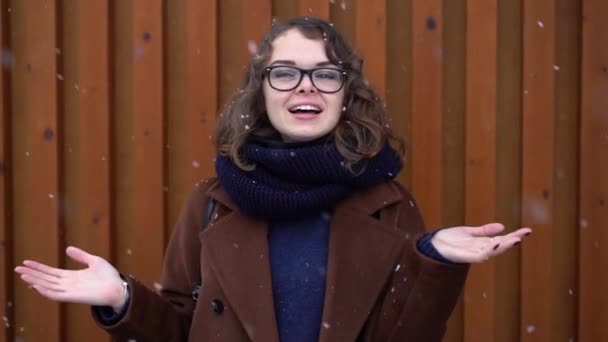 Jovem mulher bonita em chapéu vermelho de malha e cachecol desfrutando e pegando neve. Inverno — Vídeo de Stock