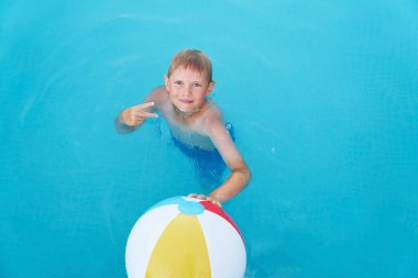 Küçük komik çocuk yüzme havuzunda topla