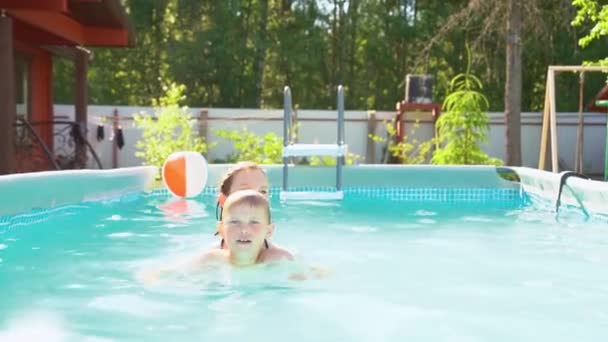 Niña divertida y niño en la piscina al aire libre. Jugar y relajarse — Vídeo de stock