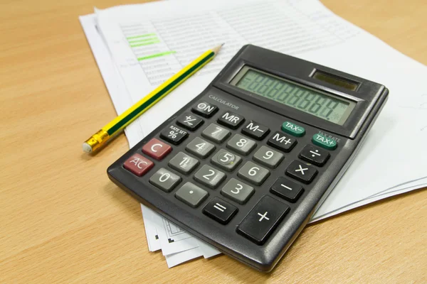 Calcolatrice e foglio di carta sul tavolo da ufficio — Foto Stock