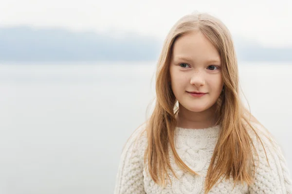 Outdoor close up portrait of a cute little girl of 8-9 years old wearing warm white knitted pullover — Stock Photo, Image