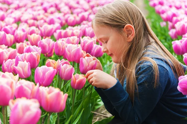 Cute dziewczynka gra z tulipany na dzień wiosny ładne — Zdjęcie stockowe