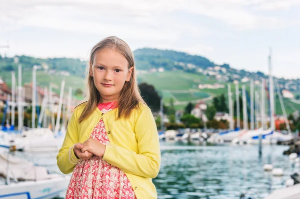 Outdoor portrait of adorable little girl of 7-8 years old, wearing party dress, resting by the lake — Stock Photo, Image