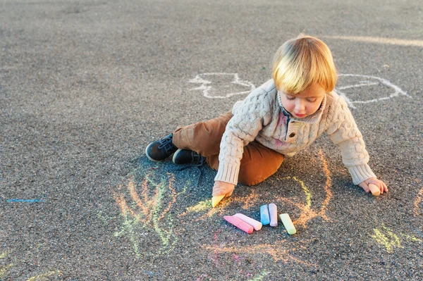 Chłopak ładny maluch rysowanie kredą na miły dzień na zewnątrz — Zdjęcie stockowe