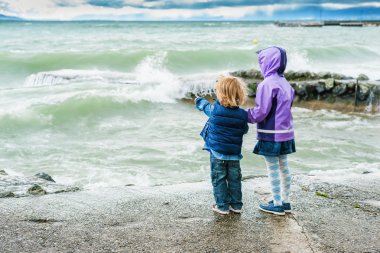 Çok güzel çocuklar göl yanındaki fırtınalı bir günde, oyun arkadan görünüm