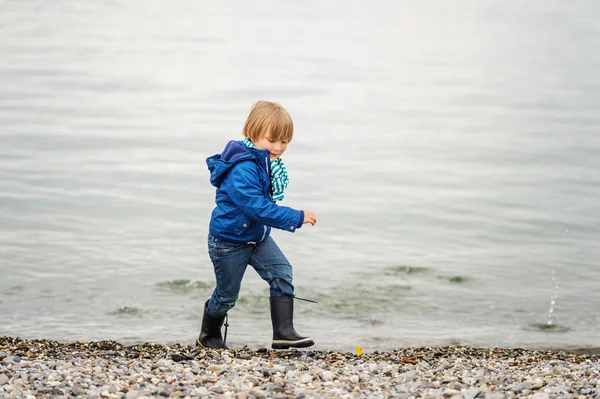 Little boy playing by the lake on a cloudy day — Stock Photo, Image