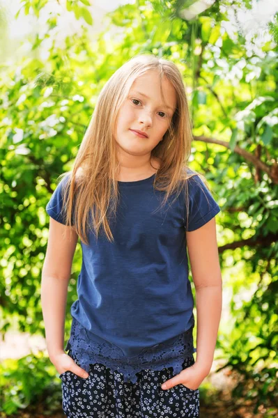 Portret van een schattig klein meisje van 7 jaar oud in het park op een zonnige dag, blauwe shirt dragen — Stockfoto