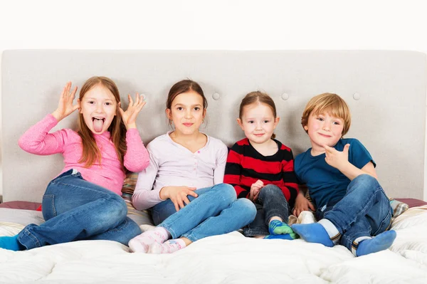 Grupo de 4 crianças, três meninas e um menino, brincando na cama dos pais — Fotografia de Stock