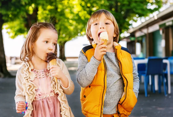 Dos niños adorables, niño y niña comiendo helado al aire libre . — Foto de Stock