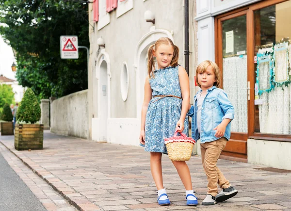 Portrét módy děti v městě, roztomilé děti pózuje venku, roztomilá holčička a její bratr na sobě modré šaty — Stock fotografie