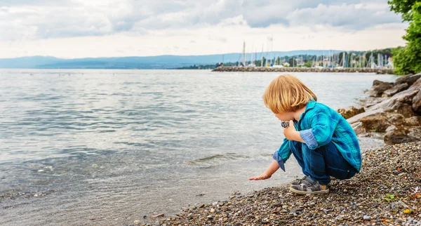 Bedårande liten pojke på 3-4 år gammal leker vid sjön på en trevlig dag — Stockfoto