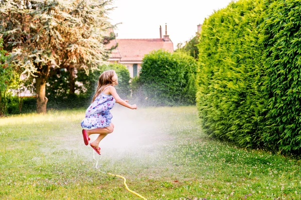 Gyermek játszó kerti locsoló, ugrott át — Stock Fotó