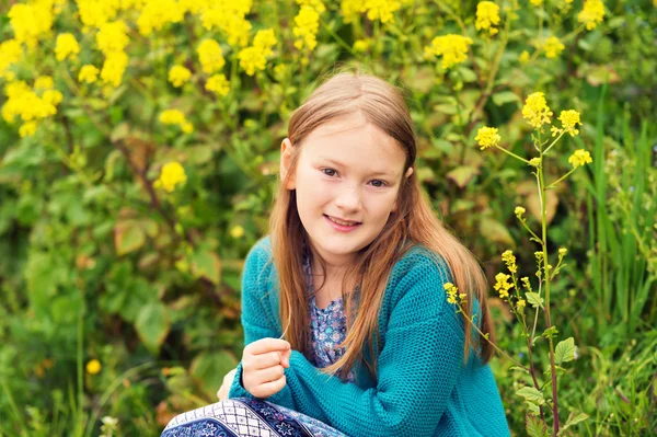 Retrato ao ar livre de uma menina bonita brincando com flores em um campo, vestindo casaco de malha de esmeralda quente — Fotografia de Stock